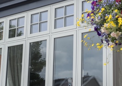 Angled close-up of Deceuninck Heritage Flush casement windows with Georgian bars, showing the sash sitting flush with the frame