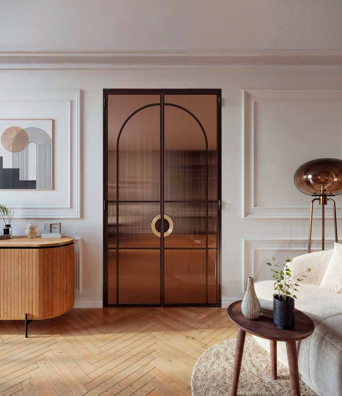 Arched steel double doors in a bronze finish with round pull handles, set in a panelled wall