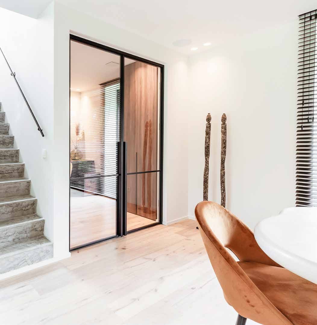 Black steel and glass door with a matching side panel at the foot of a staircase