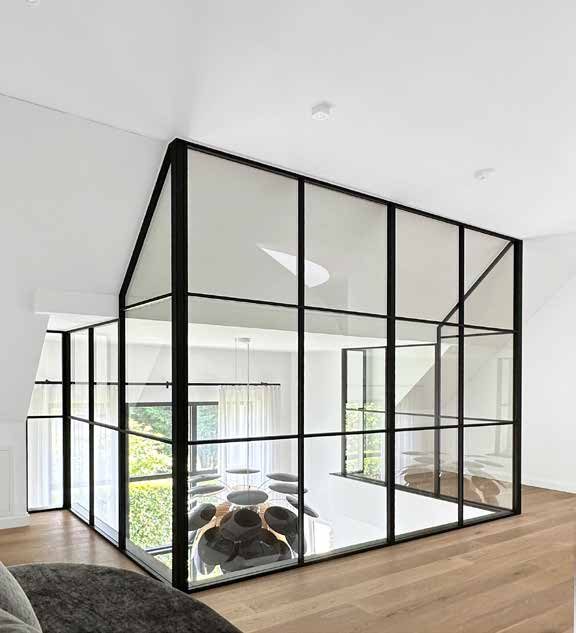Black steel and glass partition walls enclosing a room under a sloping ceiling
