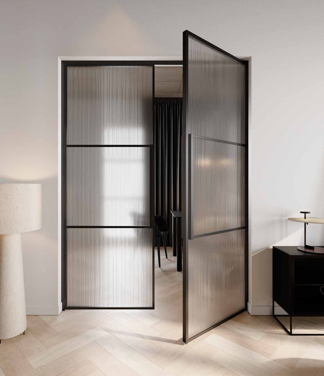 Black steel pivot door with fluted glass, half open in a bright room